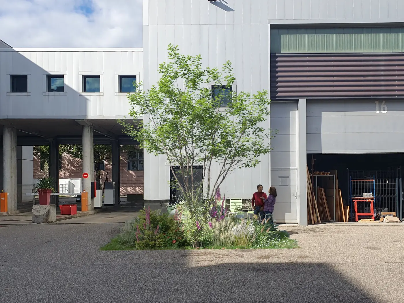 Après travaux : au même endroit, un arbre et un massif de vivaces en fleurs occupent la bande désimperméabilisée, devant le même bâtiment.
